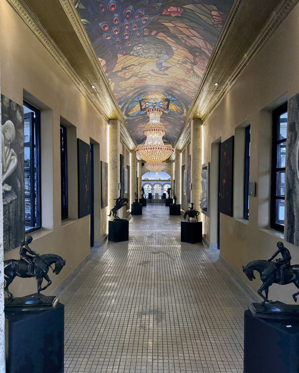 Palacio Nacional, Medellín. The corridor under the painted vault, with two equestrian bronzes facing each other on black plinths.